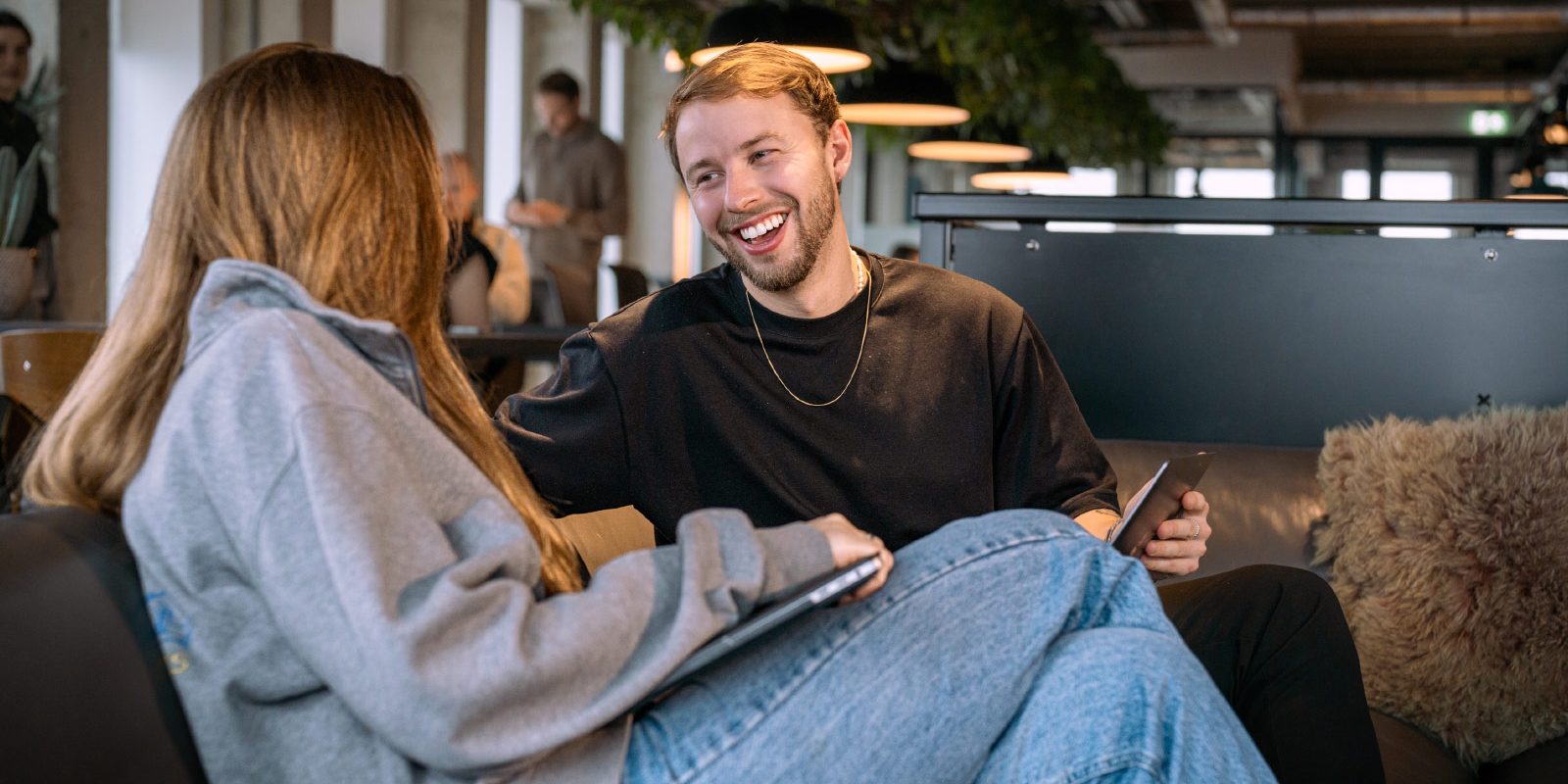 Twee lachende mensen op de bank bij de coworking space van A'DAM&Co.work in de A'DAM Toren Amsterdam