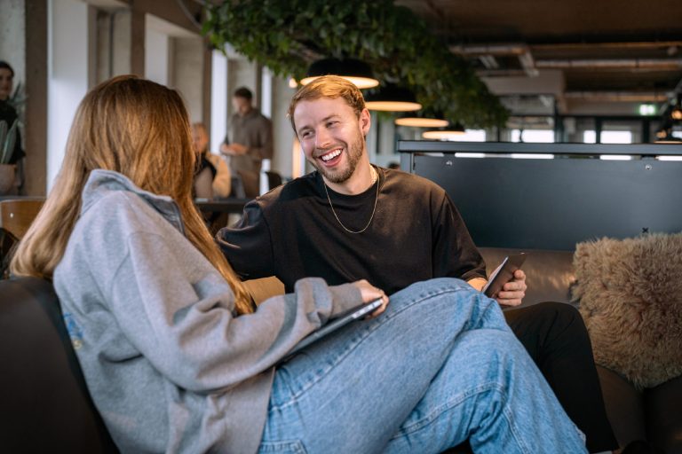 Twee lachende mensen op de bank bij de coworking space van A'DAM&Co.work in de A'DAM Toren Amsterdam