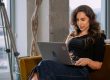 Een vrouw die op de bank zit met haar laptop op schoot bij de coworking space van A'DAM&Co.work in de A'DAM Toren Amsterdam